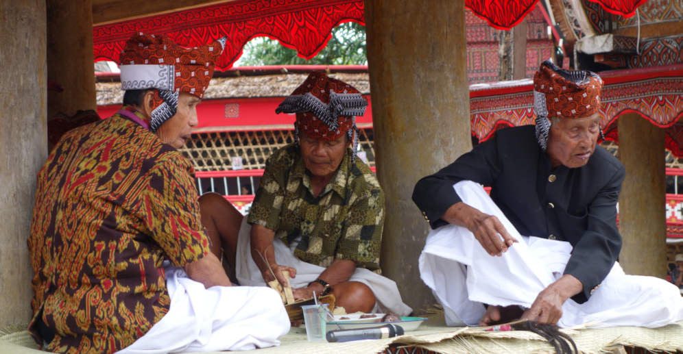 Toraja elders in traditional dress attending wake ceremony.