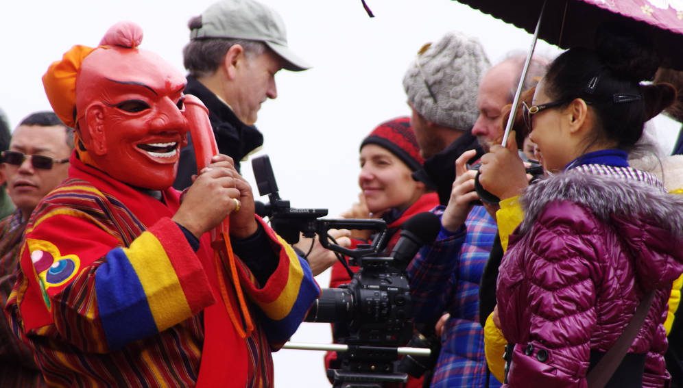 A local artist entertaining tourists and a fliming crew in Bhutan. According to the UN World Tourism Organization (UNWTO), the global tourist industry was among the hardest hit by the COVID-19 pandemic. Photo: Courtesy of Tourism Council of Bhutan.