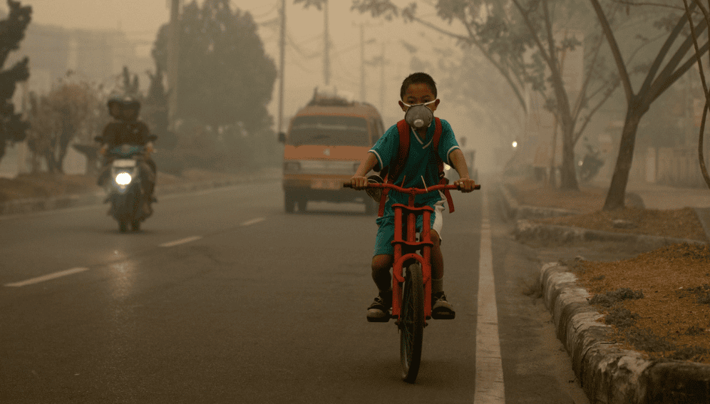 A student goes to school wearing a mask to protect him from the smoke that blankets the city of Palangka Raya, Central Kalimantan.
